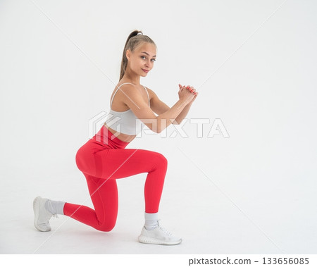 Young woman doing lunges on white cyclorama background. Vertical video. Young woman doing lunges on white cyclorama background. Vertical video. 133656085