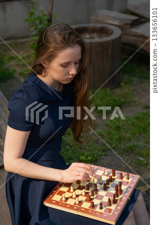 Caucasian woman playing chess outdoors. Caucasian woman playing chess outdoors. 133656101