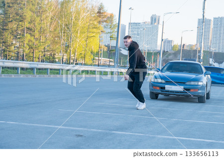 Caucasian man pulling a car with a rope.  133656113