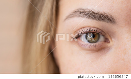 Close-up of a woman's eye after eyelash lamination procedure. Close-up of a woman's eye after eyelash lamination procedure. 133656247