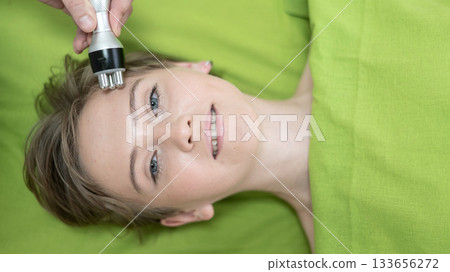 Top view of Caucasian woman undergoing radio wave RF lifting procedure in beauty salon. Top view of Caucasian woman undergoing radio wave RF lifting procedure in beauty salon. 133656272