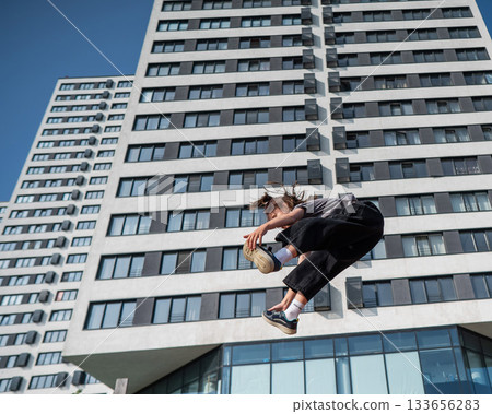 A girl jumps on an outdoor trampoline. 133656283