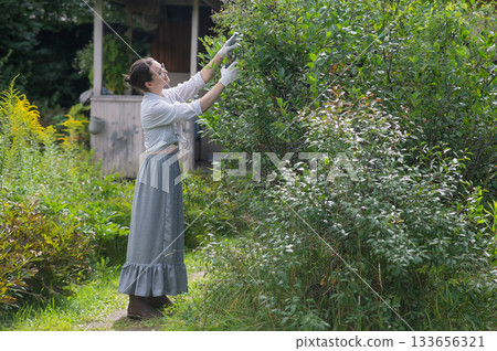 Young Caucasian woman trimming bushes.  133656321