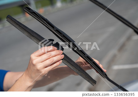 Close up of female hands changing windshield wipers. Close up of female hands changing windshield wipers. 133656395