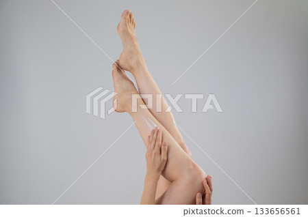 Woman applying moisturizer to her legs. White background.  133656561
