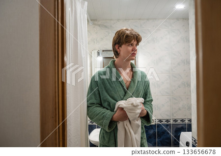 Young caucasian happy man in green bathrobe with white towel leaves bathroom. Daily personal care routine, self-care. Morning Shaving Routine Young caucasian happy man in green bathrobe with white towel leaves bathroom. Daily personal care routine, self-care. Morning Shaving Routine 133656678
