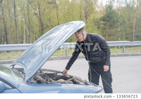Caucasian man looking under the hood of his car. Caucasian man looking under the hood of his car. 133656723