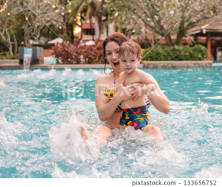 Caucasian woman holds her son while swimming in a pool on vacation. Mom teaches little boy to swim. Caucasian woman holds her son while swimming in a pool on vacation. Mom teaches little boy to swim. 133656752