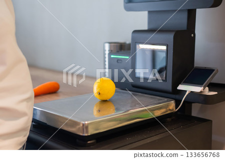 Woman weighing a lemon at a self-checkout.  133656768