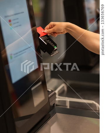 Woman paying with credit card at self-checkout. Woman paying with credit card at self-checkout. 133656769