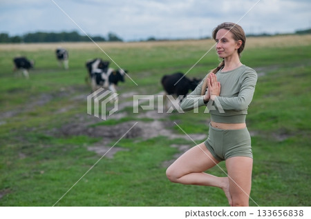 Caucasian woman doing yoga in rural area among herd of cows.  133656838