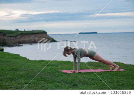 Caucasian woman doing yoga on the river bank. Caucasian woman doing yoga on the river bank. 133656839