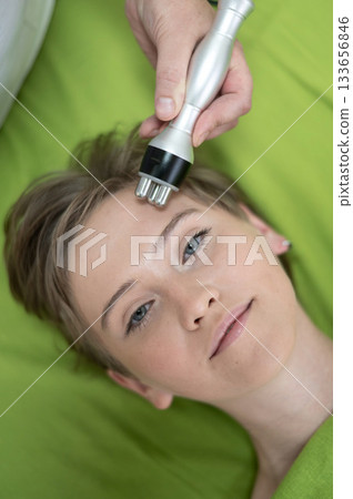 Top view of Caucasian woman undergoing radio wave RF lifting procedure in beauty salon. Top view of Caucasian woman undergoing radio wave RF lifting procedure in beauty salon. 133656846