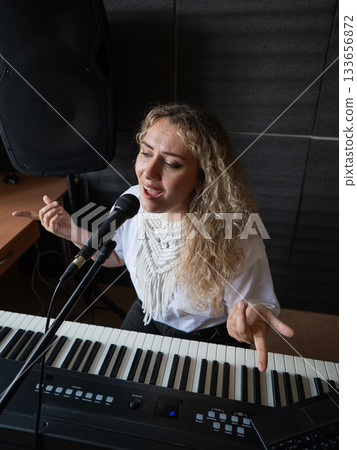 Caucasian woman singing into microphone and recording herself on laptop.  133656872