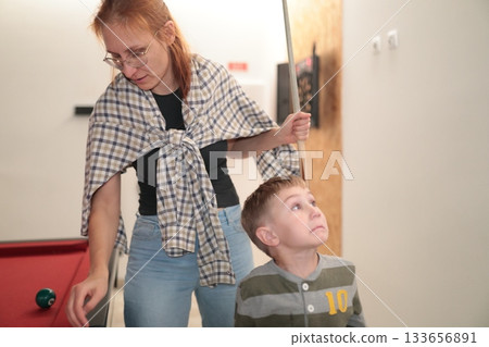 Mother teaching son playing billiards at home Mother teaching son playing billiards at home 133656891