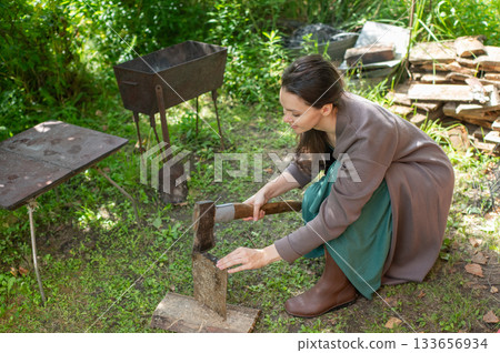 Caucasian woman chopping wood to light a barbecue.  133656934