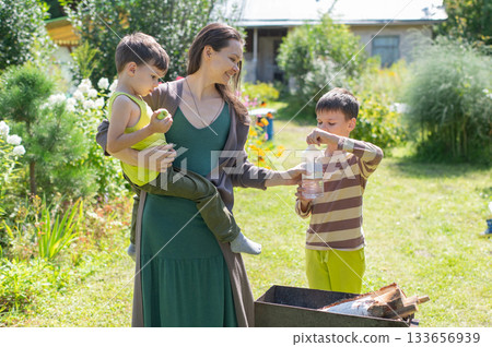 Caucasian woman lights a barbecue with her sons.  133656939