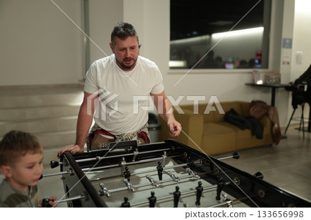 Father and son playing foosball together indoors 133656998