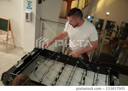 Man playing tabletop foosball game for leisure Man playing tabletop foosball game for leisure 133657005