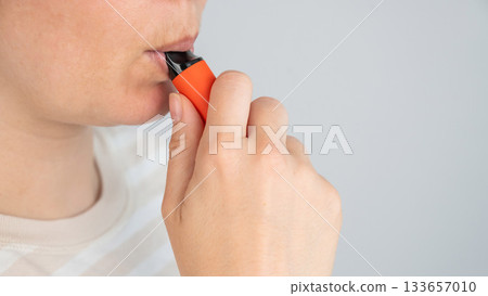 Caucasian woman smoking disposable vape.  133657010