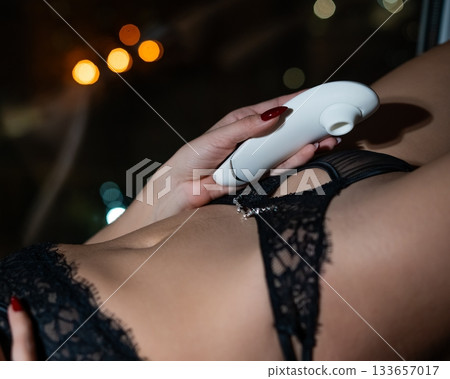 Woman using white clitoral vacuum stimulator.  133657017