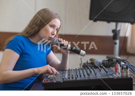 Young woman mixing live sound. Girl recording a song in the studio. Young woman mixing live sound. Girl recording a song in the studio. 133657026