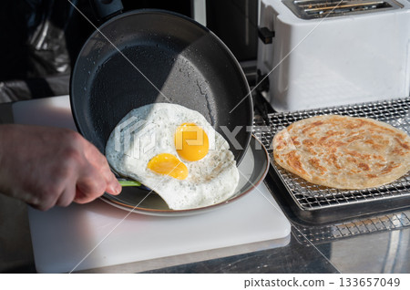 The chef fries the eggs sunny side up. The chef fries the eggs sunny side up. 133657049