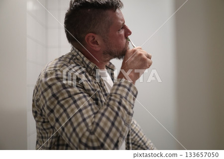 Man brushing teeth maintaining oral hygiene routine 133657050