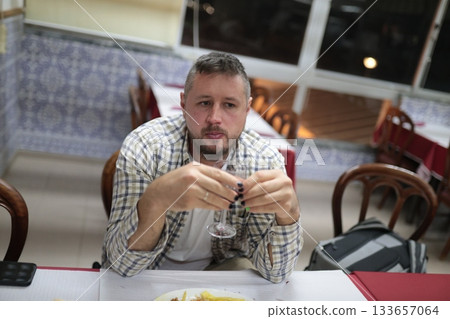 Man holding glass feeling thoughtful in restaurant or bar 133657064