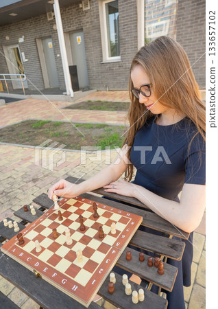 Caucasian woman playing chess outdoors. Caucasian woman playing chess outdoors. 133657102