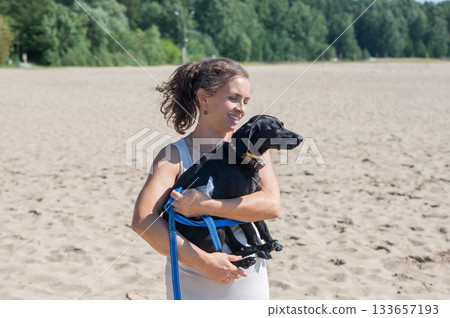 Caucasian woman walking on the beach with her dog.  133657193