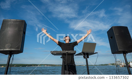 Male DJ playing music on the beach.  133657302