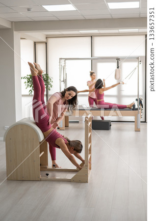 A trainer adjusts woman on a Ladder Barrel. A trainer adjusts woman on a Ladder Barrel. 133657351