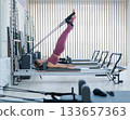 Asian woman doing Pilates on reformer machine.  133657363