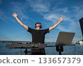Male DJ playing music on the beach.  133657379