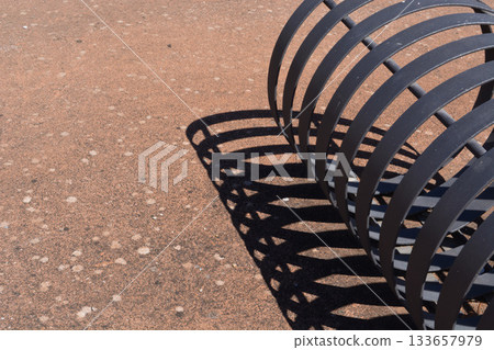 A bicycle rack casts a shadow on the ground on a sunny day. Concept: abstraction, geometry, cycling elements, sustainable consumption, carbon footprint. 133657979