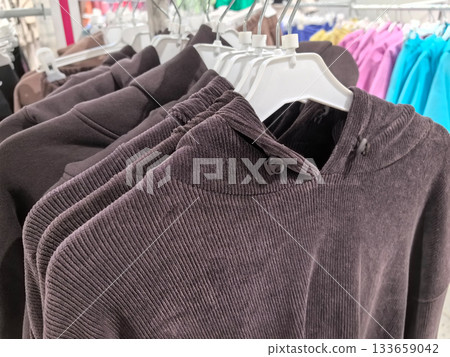 Gray hoodies displayed on hangers in a bright clothing store 133659042