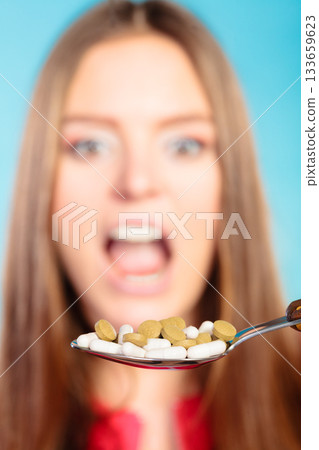 Young woman eating pills on a spoon Young woman eating pills on a spoon 133659623