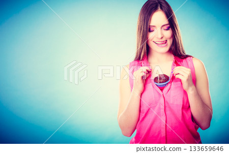 Funny woman holds chocolate cake on chest Funny woman holds chocolate cake on chest 133659646