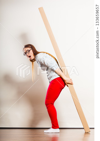 Woman moving into apartment carrying heavy box. Woman moving into apartment carrying heavy box. 133659657