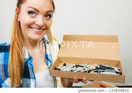 Girl holding parts tools for furniture assembling. Girl holding parts tools for furniture assembling. 133659658