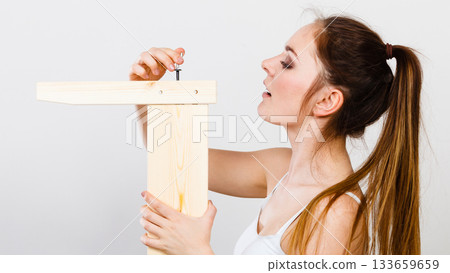 Woman assembling wooden furniture. DIY. Woman assembling wooden furniture. DIY. 133659659