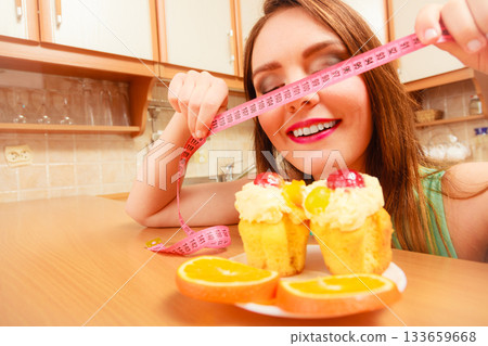 Woman with tape measure and cake. Diet dilemma. 133659668