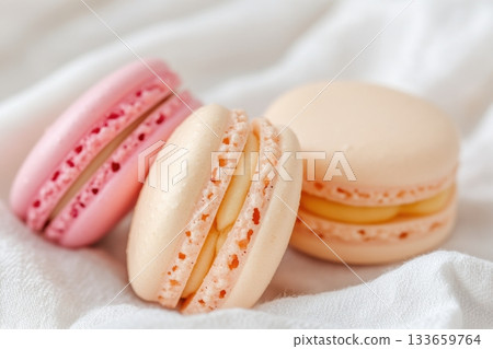 Delightful assortment of macarons in pastel colors arranged on soft fabric 133659764