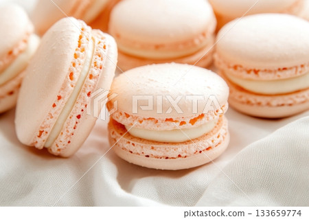 Delicate pastel macarons arranged elegantly on a white fabric surface, showcasing their smooth texture and inviting colors perfect for dessert lovers 133659774