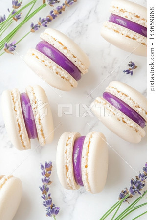 Delicate lavender macarons arranged artistically on a marble surface with natural lavender sprigs enhancing the aesthetic appeal 133659868