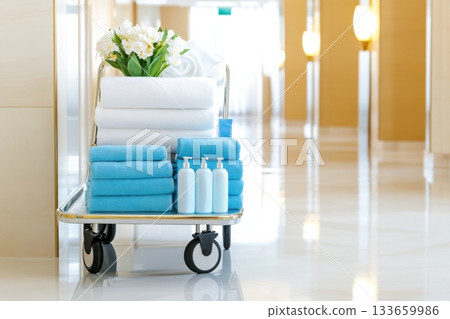 Fresh towels and toiletries arranged neatly on a service cart in a luxurious hotel hallway during daytime 133659986