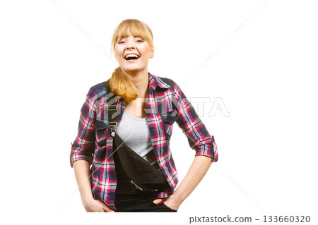 Standing woman wearing dungarees laughing Standing woman wearing dungarees laughing 133660320