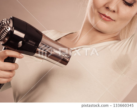 Woman drying armpit with hair dryer Woman drying armpit with hair dryer 133660345