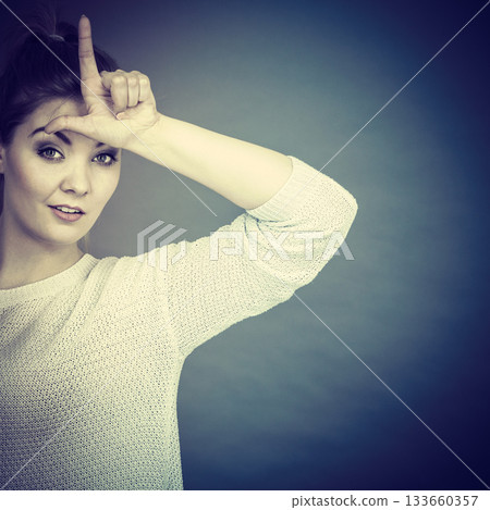 Woman showing loser gesture with L on forehead Woman showing loser gesture with L on forehead 133660357